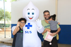Família ao lado do Zé Gotinha durante ação de vacinação no Distrito Federal