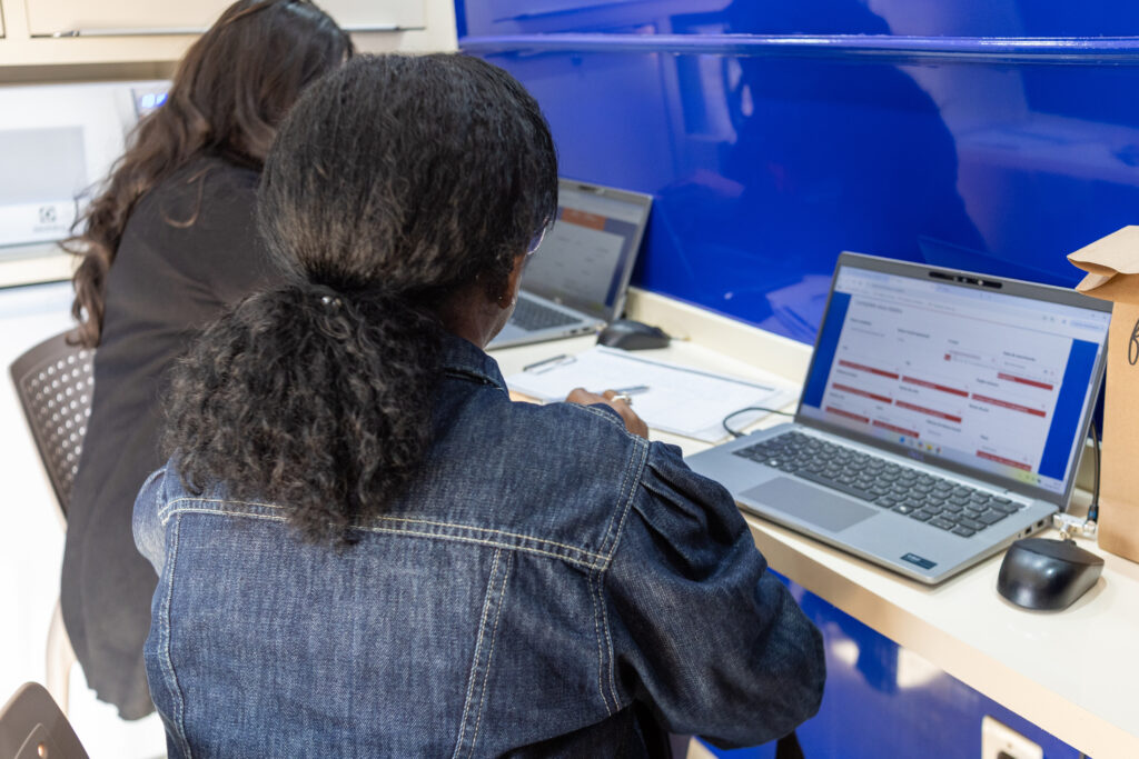 Mulher recebe orientação diante de computadores em unidade do Centro de Referência da Mulher Brasileira