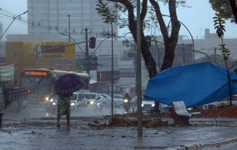 Pedestre e veículos circulam sob chuva intensa no Distrito Federal