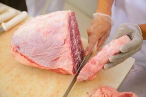 Açougueiro corta peça de carne durante o trabalho em estabelecimento do Distrito Federal