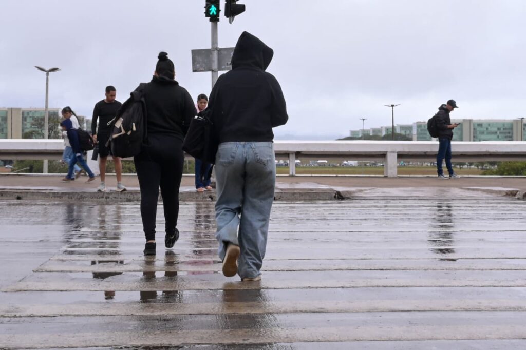 Pedestres caminham sob chuva na área central de Brasília