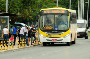 Ônibus do transporte público do DF circula em via próxima a uma parada com passageiros