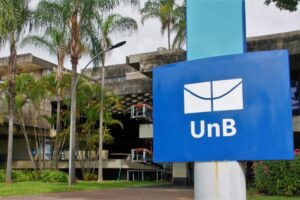 Placa com a marca da Universidade de Brasília diante de prédio do campus
