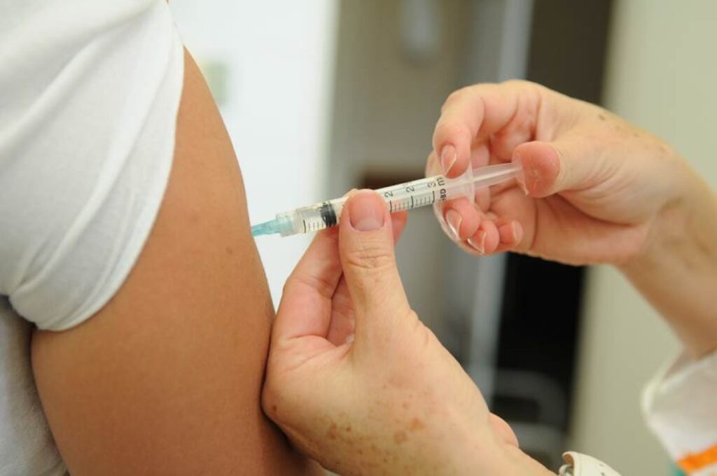 Profissional de saúde aplica vacina no braço de uma pessoa